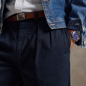Model wearing Ralph Lauren Aviator Navy chino trousers, styled with a denim jacket, grey top, brown leather belt, and blue chronograph watch.