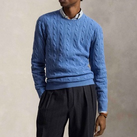 Model wearing Ralph Lauren cable-knit crew neck jumper in Turquoise Jay Heather, styled with a white shirt collar and dark trousers.