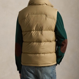 Model wearing Ralph Lauren desert khaki quilted down gilet, styled with green long-sleeve top and blue jeans, seen from behind.
