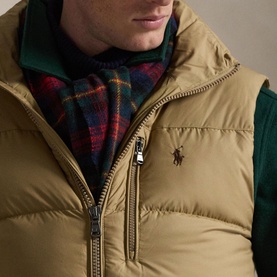 Model wearing Ralph Lauren desert khaki quilted gilet with gold-tone zip, styled with green jacket and tartan scarf