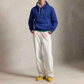 Model wearing Ralph Lauren RL Pony Logo Fleece Hoodie in Blue Yacht with white wide-leg trousers and yellow trainers.