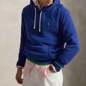 Model wearing Ralph Lauren RL Pony Logo Fleece Hoodie in Blue Yacht with drawstring hood and kangaroo pocket, styled with white trousers