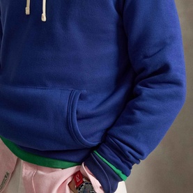 Model wearing Ralph Lauren The RL Pony Logo Fleece Hoodie in Blue Yacht, close-up showing kangaroo pocket, ribbed cuffs, and cream drawstring.