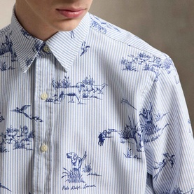 Model wearing Ralph Lauren Dog & Pheasant Logo Striped Oxford Shirt in blue and white with toile scenic print and button-down collar.