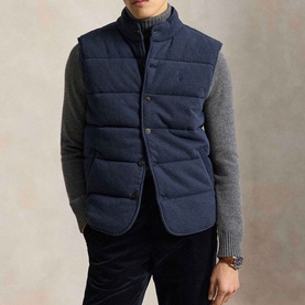 Model wearing Ralph Lauren navy herringbone quilted gilet over grey roll-neck sweater, button-front fastening with stand collar