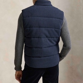 Model wearing Ralph Lauren navy heather dogtooth quilted gilet, styled with grey knit sweater and dark trousers, rear view.