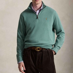 Model wearing Ralph Lauren pine heather half-zip sweatshirt with embroidered logo, styled with dark corduroy trousers and brown belt.