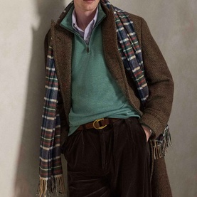 Model wearing Ralph Lauren Pine Heather half-zip sweatshirt, styled with brown tweed overcoat, plaid scarf and dark corduroy trousers.