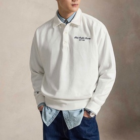 Model wearing Ralph Lauren white polo-collar sweatshirt with navy script logo, styled over a blue chambray shirt.