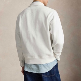 Model wearing Ralph Lauren white sweatshirt, back view, styled with light blue shirt and dark navy jeans.