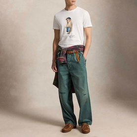 Model wearing Ralph Lauren Polo Bear Custom Slim Fit T-Shirt in white with green trousers and brown loafers, jacket tied at waist.