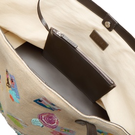 Staud Beach Day Tote interior view showing zip pocket, cream canvas lining, and dark brown leather trim detail