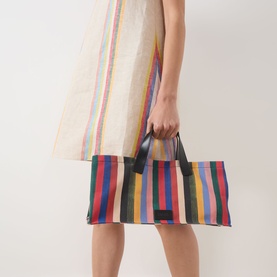 Model carrying Staud Port Stripe Tote Bag in Artist Stripe, boxy silhouette with leather top handles, bold multicolour vertical stripes
