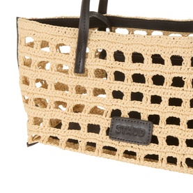 Staud Tote in raffia crochet with open-weave pattern, dark leather trim handles and branded logo patch detail.
