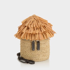 Staud beige raffia tote bag with fringed thatched roof lid, hut shape, and dark leather crossbody strap