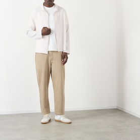Model wearing Wax London Corey Striped Shirt in Natural, long sleeve with pointed collar, styled with beige trousers and white trainers.