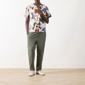 Model wearing Wax London Didcot Abstract Print Shirt in ecru/multi with camp collar, styled with olive trousers and white trainers.