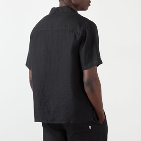 Model wearing Wax London Didcot Linen Bowling Shirt in black, rear view showing short sleeves and straight hemline.