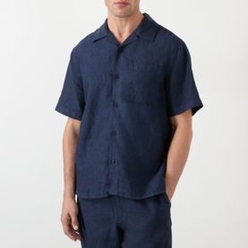 Model wearing Wax London navy linen casual shirt with camp collar, short sleeves and chest pocket, styled with matching navy trousers.