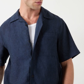 Model wearing Wax London navy linen casual shirt with camp collar and chest pocket, styled with a white crew-neck T-shirt underneath.