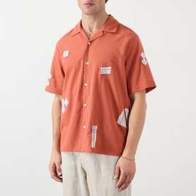 Model wearing Wax London Didcot Scribble Casual Shirt in terracotta with ecru appliqu&eacute; patches, short sleeves, spread collar, paired with linen
