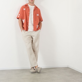 Model wearing Wax London Didcot Scribble Casual Shirt in terracotta with ecru squiggle applique, styled with striped tee and beige trousers.