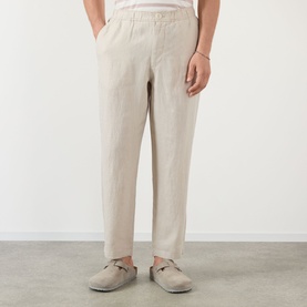 Model wearing Wax London Kurt Linen Relaxed Fit Trousers in beige, styled with tan loafers. Relaxed straight-leg silhouette with elasticated