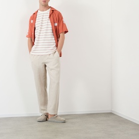 Model wearing Wax London Kurt Linen Relaxed Fit Trousers in beige, styled with a coral short-sleeve shirt and striped tee.