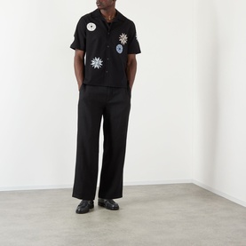 Model wearing Wax London Glencoe Linen Trousers in black, straight leg fit, styled with a black patch shirt and black loafers.