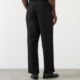 Model wearing Wax London Glencoe Linen Trousers in black, straight-leg fit with elasticated waist, styled with black leather shoes.