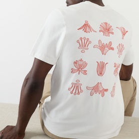 Model wearing Wax London Dean Logo Embroidery T-Shirt in ecru, showing rust floral back embroidery print detail, seated pose