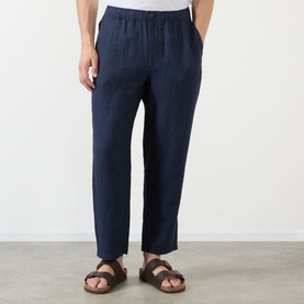 Model wearing Wax London navy linen casual trousers with elasticated waist, styled with brown leather sandals.
