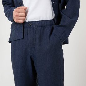 Model wearing Wax London navy linen casual trousers with elasticated waist, styled with matching navy linen jacket and white T-shirt.