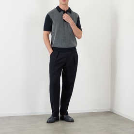 Model wearing Wax London Turin Knitted Polo Shirt in navy with black trousers and loafers. Ribbed trim, buttoned placket, short sleeves.