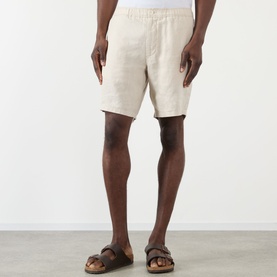 Model wearing Wax London Kurt Linen Shorts in beige, mid-rise straight leg style, paired with brown leather sandals.