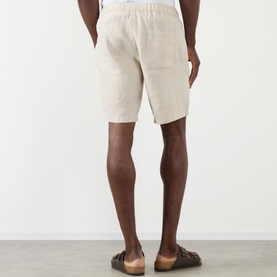 Model wearing Wax London Kurt Linen Shorts in beige, back view, styled with brown leather sandals.