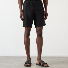 Model wearing Wax London Kurt Linen Shorts in black, styled with black leather sandals.