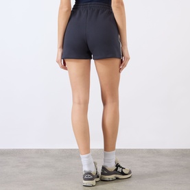 Model wearing Adanola Midnight Blue cotton shorts with white stripe detail, styled with white socks and grey trainers, back view