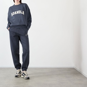 Model wearing Adanola ADA Logo Sweatpants in Midnight Blue, slim-leg with cuffed ankles, styled with matching sweatshirt and trainers.