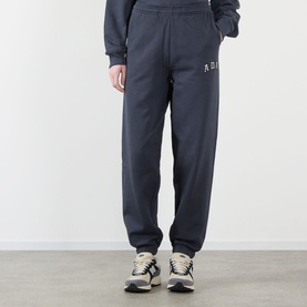 Model wearing Adanola ADA Logo Sweatpants in Midnight Blue, slim-leg cuffed joggers with chest logo, styled with grey trainers.