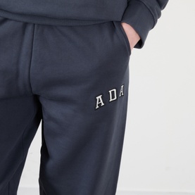 Model wearing Adanola ADA Logo Sweatpants in Midnight Blue, slim-leg fit with embroidered ADA chest logo, paired with matching sweatshirt.