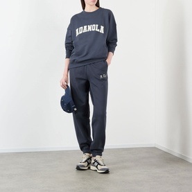 Model wearing Adanola ADA Logo Sweatpants in Midnight Blue, slim-leg cuffed style, paired with matching sweatshirt and chunky trainers