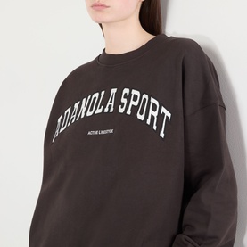 Model wearing Adanola AS Logo Oversized Sweatshirt in Coffee Bean, crew neck with white varsity-style logo print across chest