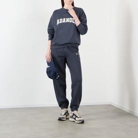 Model wearing Adanola Varsity Logo Oversized Sweatshirt in Midnight Blue with matching joggers, carrying a navy bag, styled with chunky trainers.