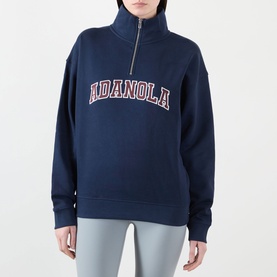 Model wearing Adanola Varsity Logo Half-Zip Sweatshirt in navy blue with burgundy logo, funnel neck, half-zip, styled with light grey leggings.