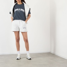Model wearing Adanola ADA Sport Oversized Logo T-Shirt in Midnight Blue with white lettering, styled with light grey shorts and white trainers.
