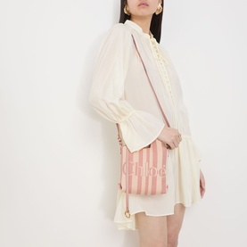 Model carrying Chloe P777 Stripy Mini Tote Bag in Nougat, pink striped canvas with jacquard logo, gold-tone hardware, worn crossbody over cream mini