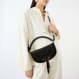 Model carrying Chloe Marcie Mini Crossbody Bag in black calfskin with gold-tone studded trim, top handle, and adjustable crossbody strap. Styled with