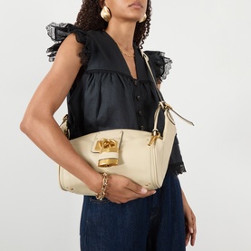 Model carrying Chloe Paddington Hobo Shoulder Bag in Cloudy Cream with gold-tone hardware and padlock charm, styled with black ruffled top and jeans