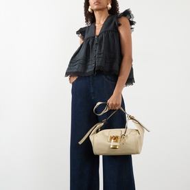 Model carrying Chloe Paddington Hobo Shoulder Bag in Cloudy Cream textured leather with gold-tone padlock charm, styled with black ruffled top and